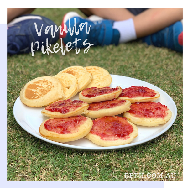 Plate of vanilla pikelets with strawberry jam.